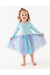 A young girl with blonde hair in a ponytail stands barefoot on a white studio floor, wearing a light blue long-sleeve top and a sparkly tulle tutu skirt in pastel blue, purple, and pink. She is holding out the sides of the skirt to show its volume. Bird and Bean Kids