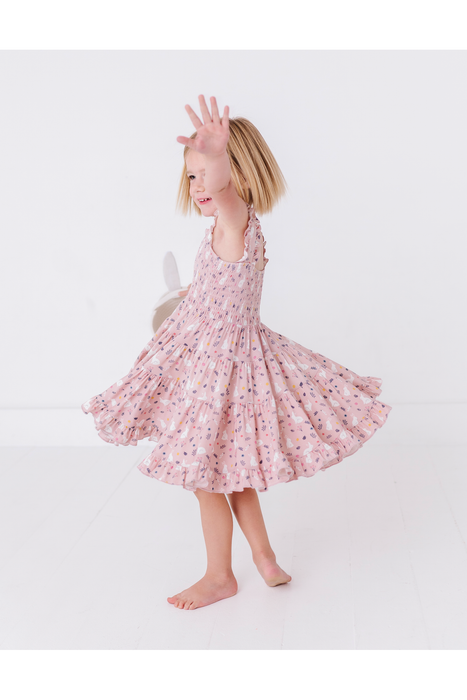 Young girl in a pink floral bunny easter dress twirling standing on a white background  Bird and Bean Kids
