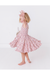 Young girl in a pink floral bunny easter dress twirling standing on a white background  Bird and Bean Kids