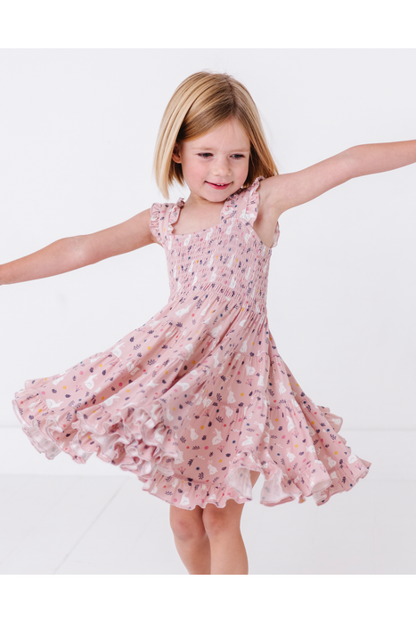 Young girl in a pink floral easter dress twirling on a white background bird and bean kids