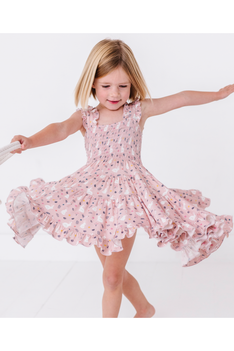Young girl in a pink bamboo floral dress twirling on a white background Bird and Bean Kids