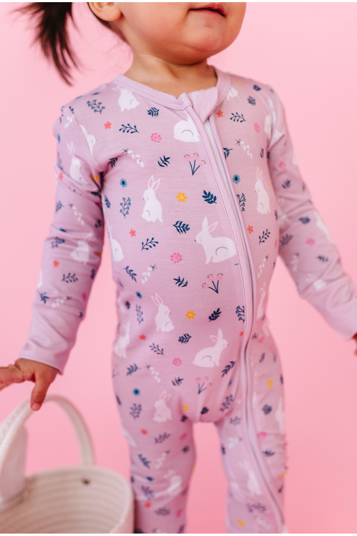 Child wearing a pink zipper front pajamas bamboo fabric with animal prints on a pink background | Global Goods Partners 