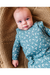 A baby lying on a brown knit blanket, wearing a long-sleeve footless bamboo TOG 1.0 sleep sack in dusty blue with a white crescent moon and star pattern. Bird and Bean Baby 