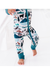 A close-up of a child wearing patterned winter pajamas with a front zipper. The pajamas have a white base with a colorful print of mountains, trees, and animals in teal, black, brown, and orange, with solid teal cuffs. Bird and Bean, into the Wild print 