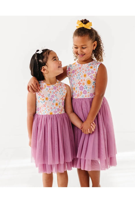 Two kid models wearing Darling Spring Daisy bamboo tulle dress with peach, lilac, golden, and sage blooms