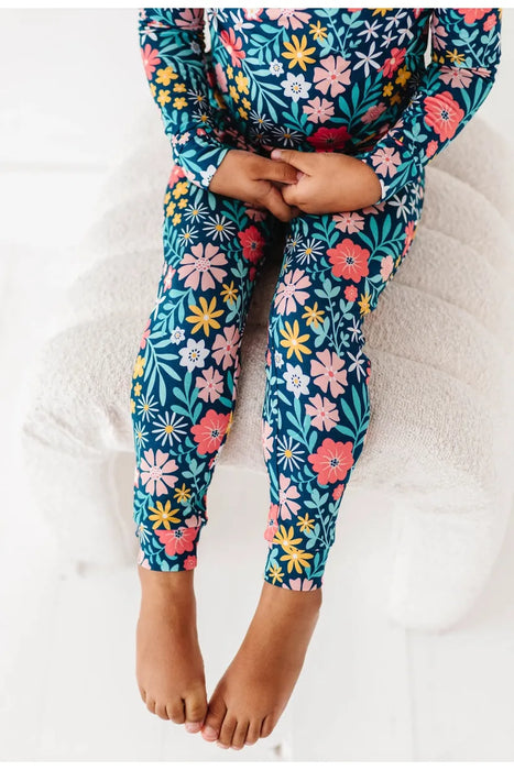 close up of child in model Bamboo Maren Peach, gold, and pink flower navy pajama set