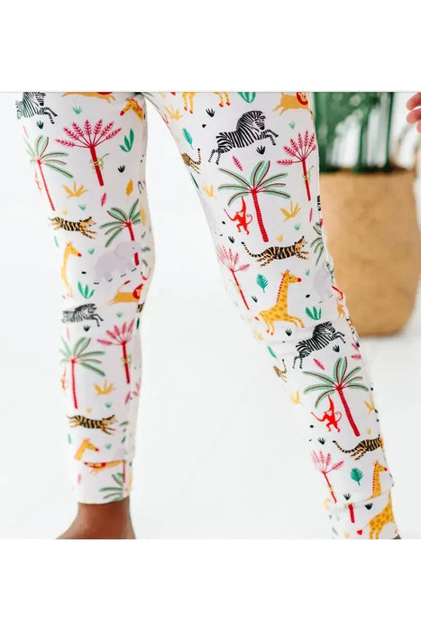 close up of kid model wearing Safari Animal print bamboo kid pajamas with zebra, lion, elephant, giraffe on cream background