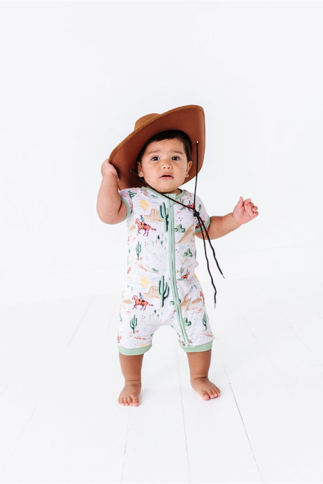 full image of baby model in a cowboy hat wearing Bird & Bean Bamboo Shortie Romper Onesie with Billy Cowboy Western Print 