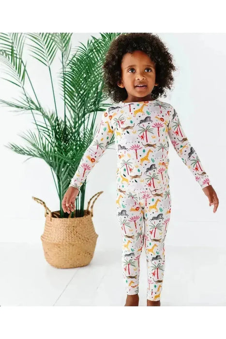 kid model wearing Safari Animal print bamboo kid pajamas with zebra, lion, elephant, giraffe on cream background